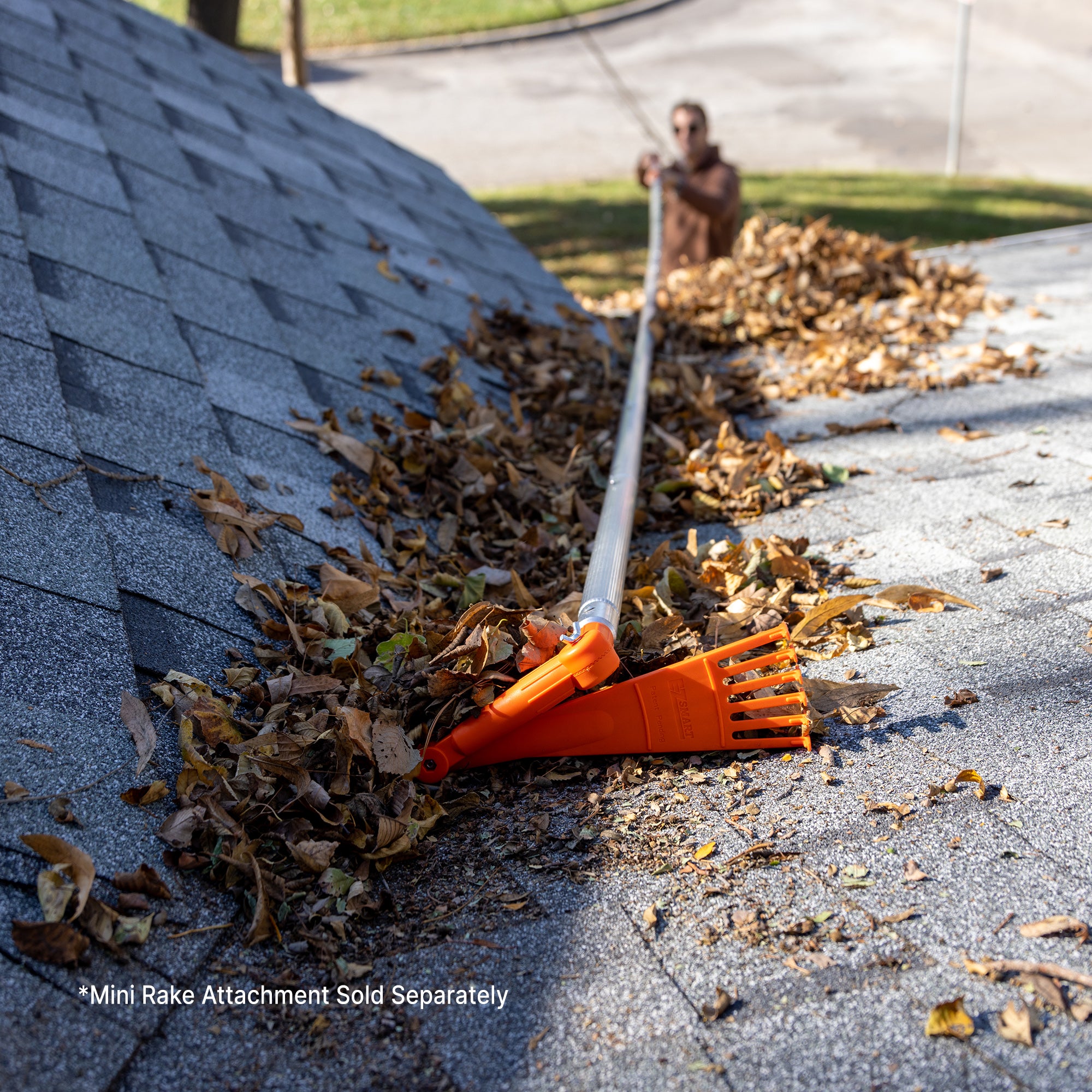 Man using 16ft extension pole kit with mini rake attachment to clear leaves (mini rake sold separately)