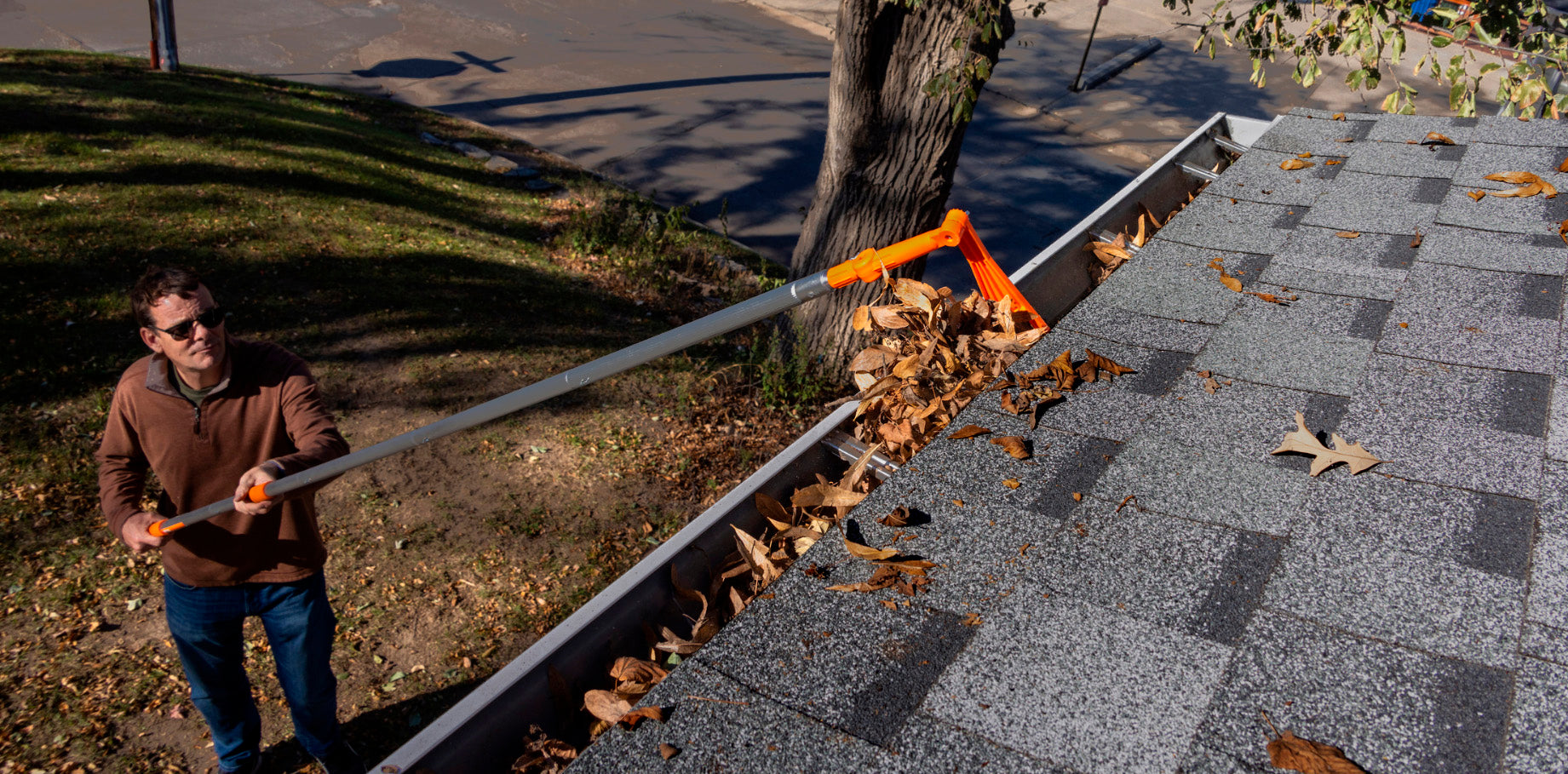 Man using adjustable Mini Roof Rake to clear leaves from a roof gutter (EZ Smart pole kit sold separately)