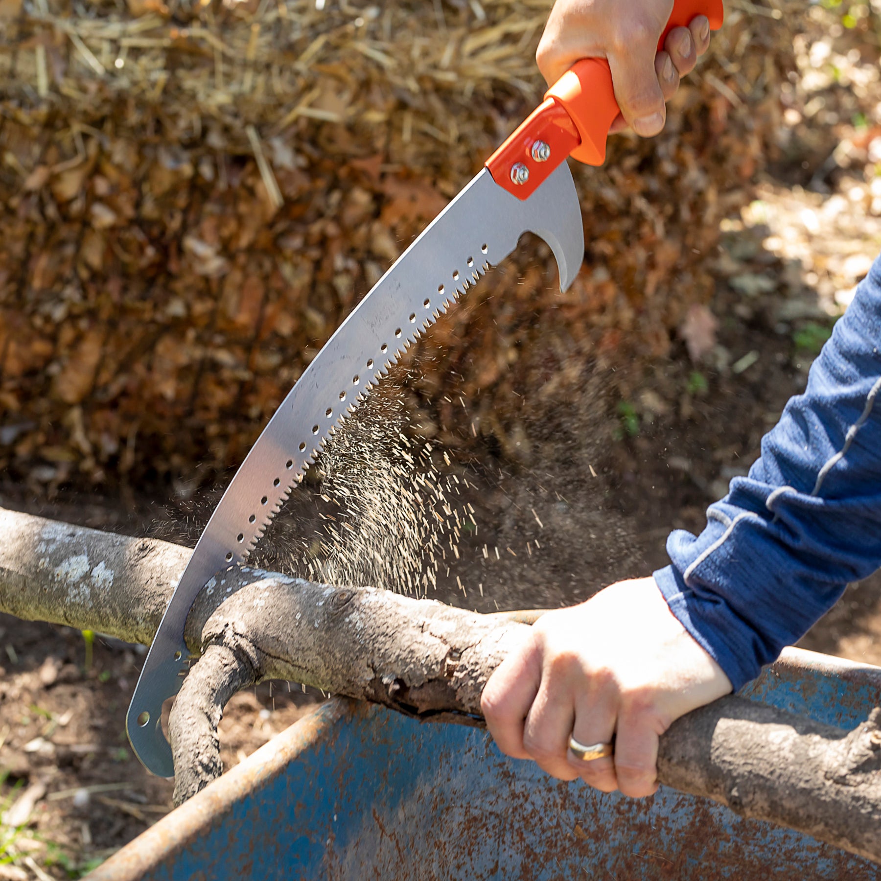 Person using 14-inch pruning saw by hand to cut branch.