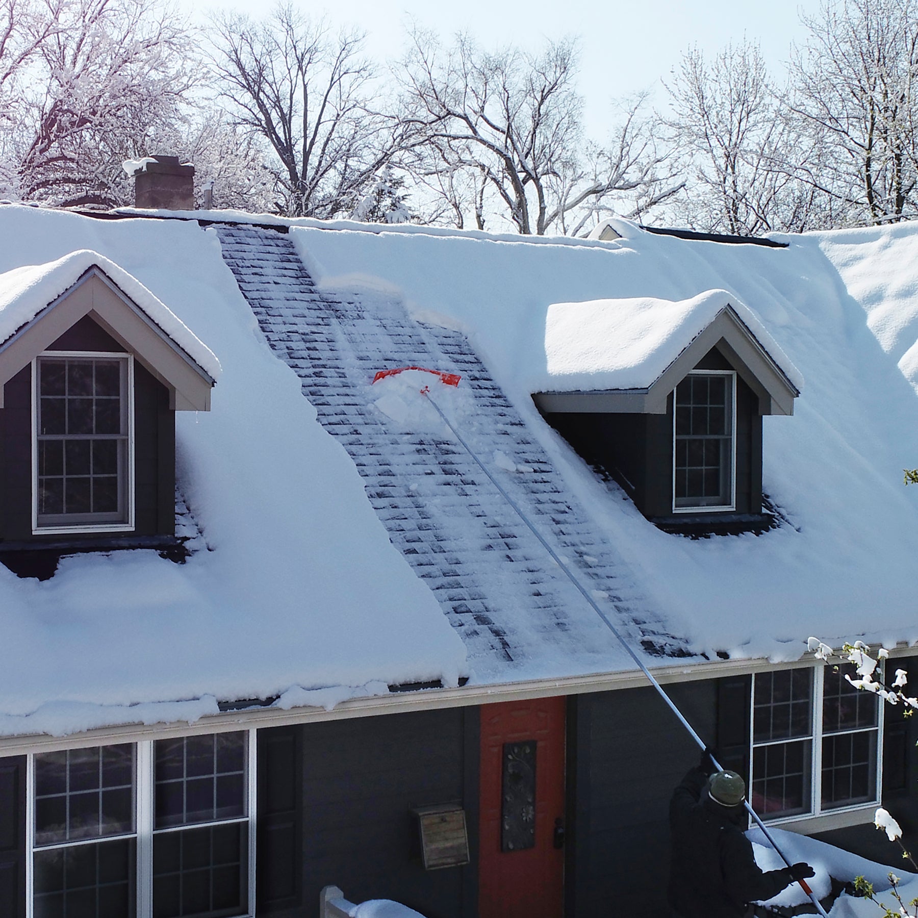 Man removing snow from roof using roof rake with 16ft extension pole.