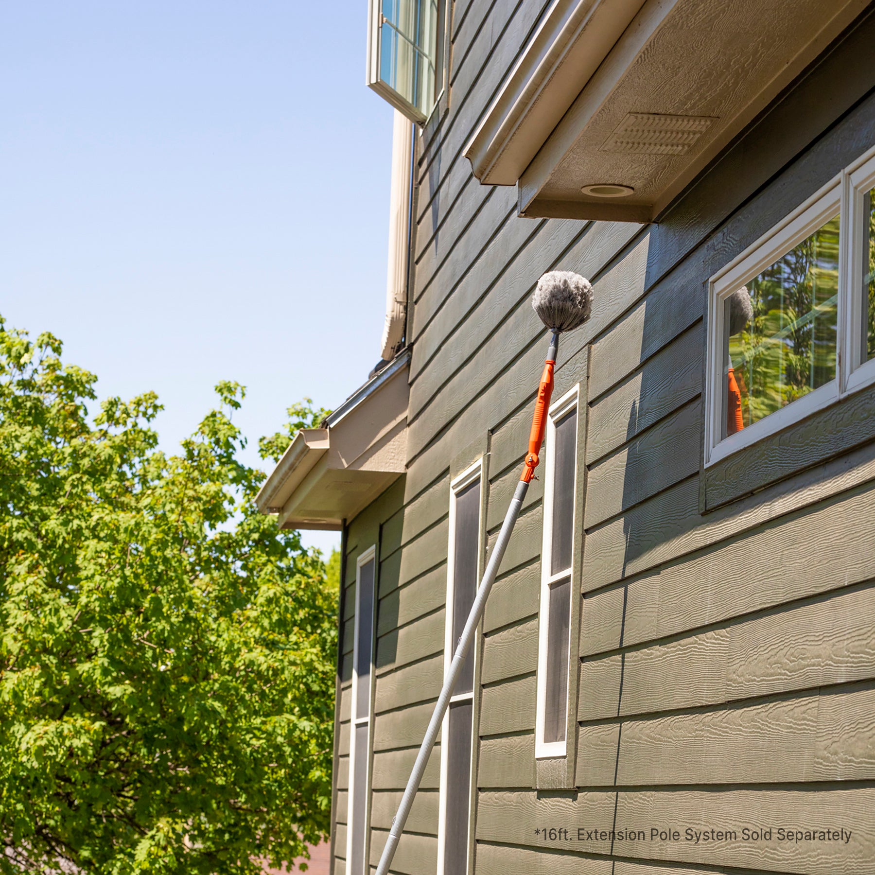 Motorized cobweb duster on extension pole cleaning overhang; extension pole sold separately.