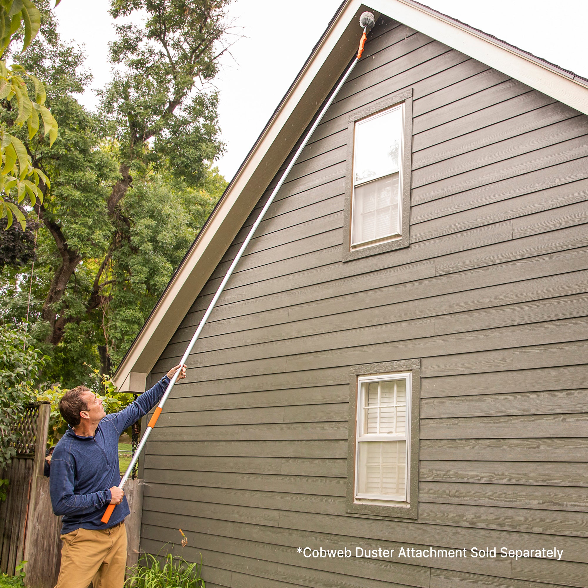 Man using 16ft extension pole kit with cobweb duster attachment to clean roof overhang. (cobweb duster sold separately)