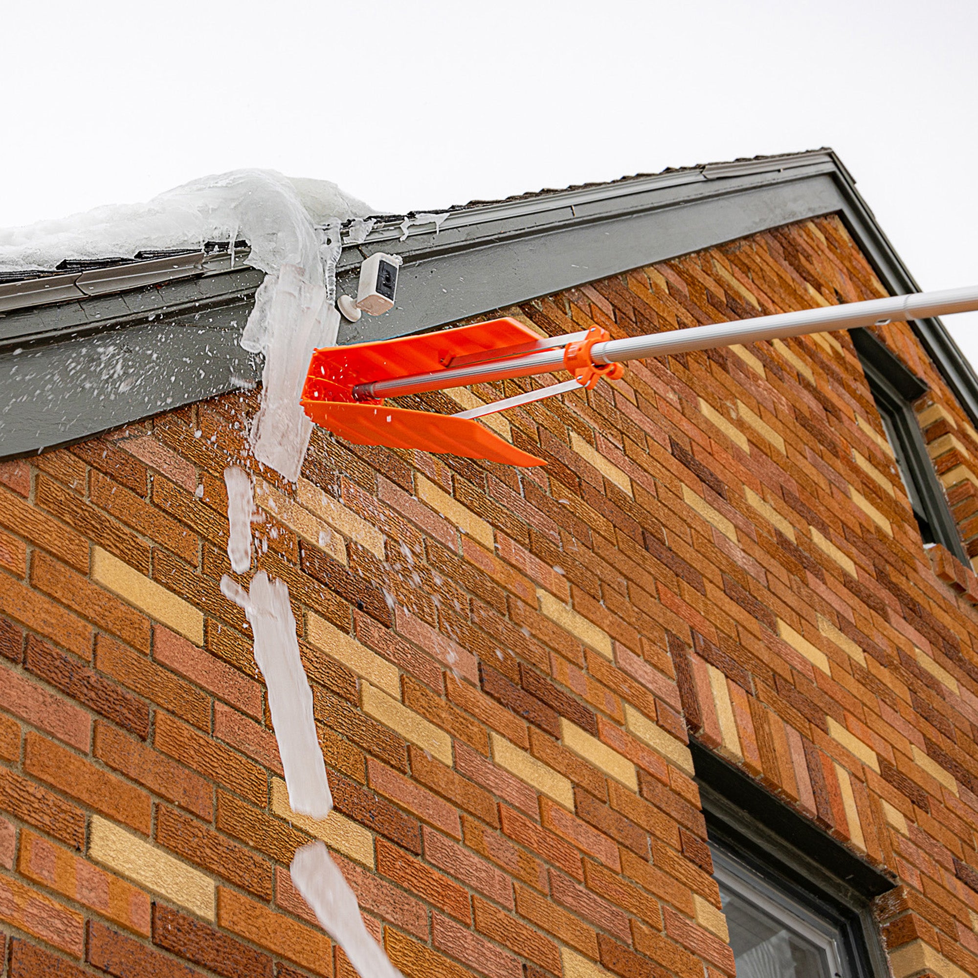 Patented adjustable snow roof rake that folds up to function as an ice scraper on a roof with ice and snow