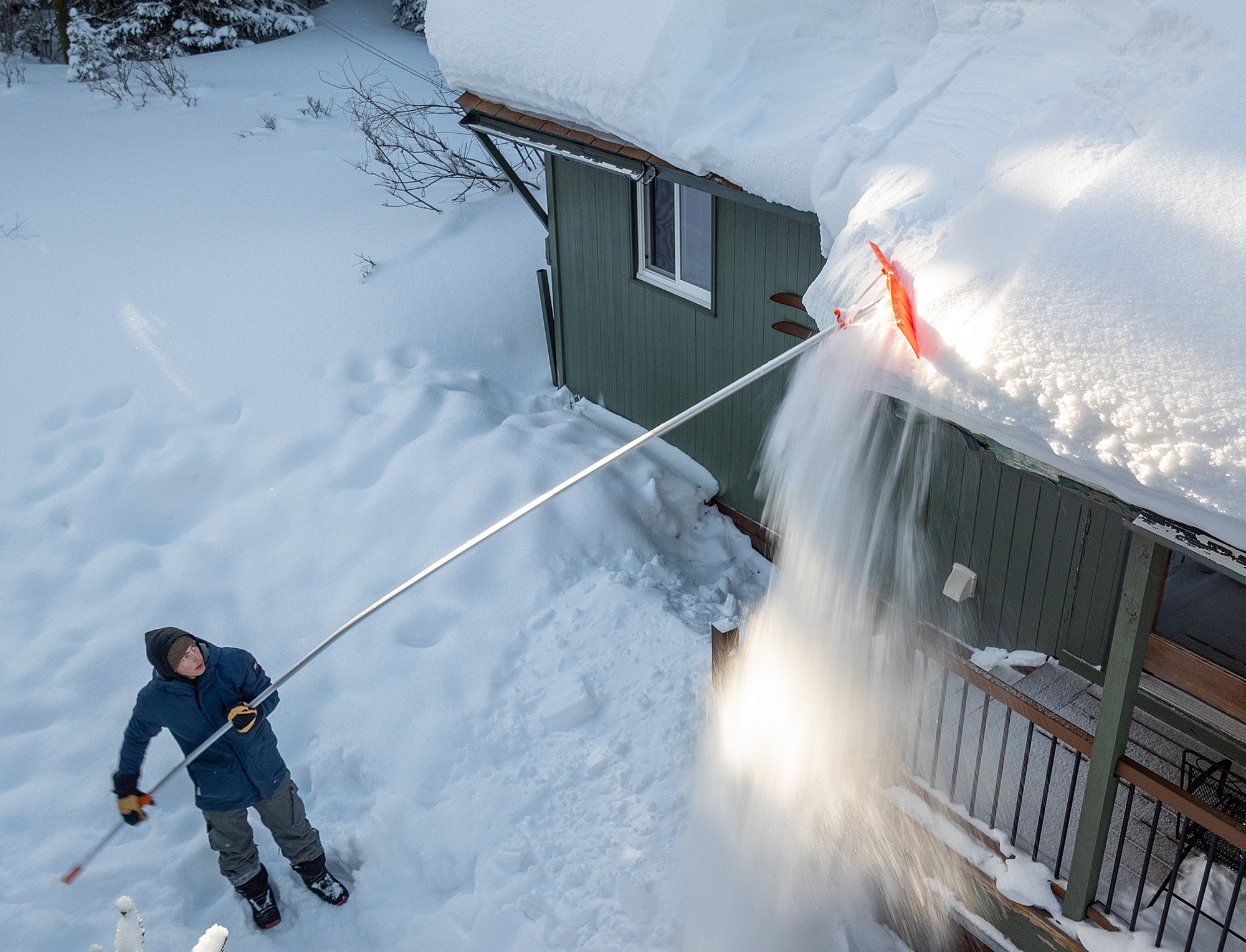 Man removing snow from roof using roof rake with 16ft extension pole kit